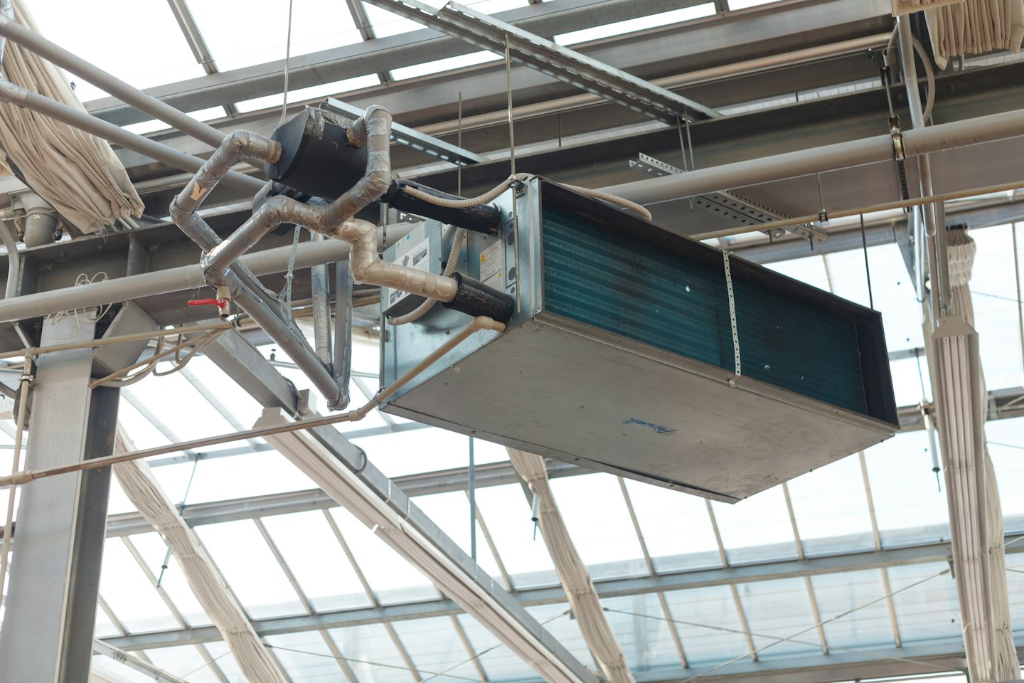 Industrial HVAC unit suspended from a glass-roofed building.